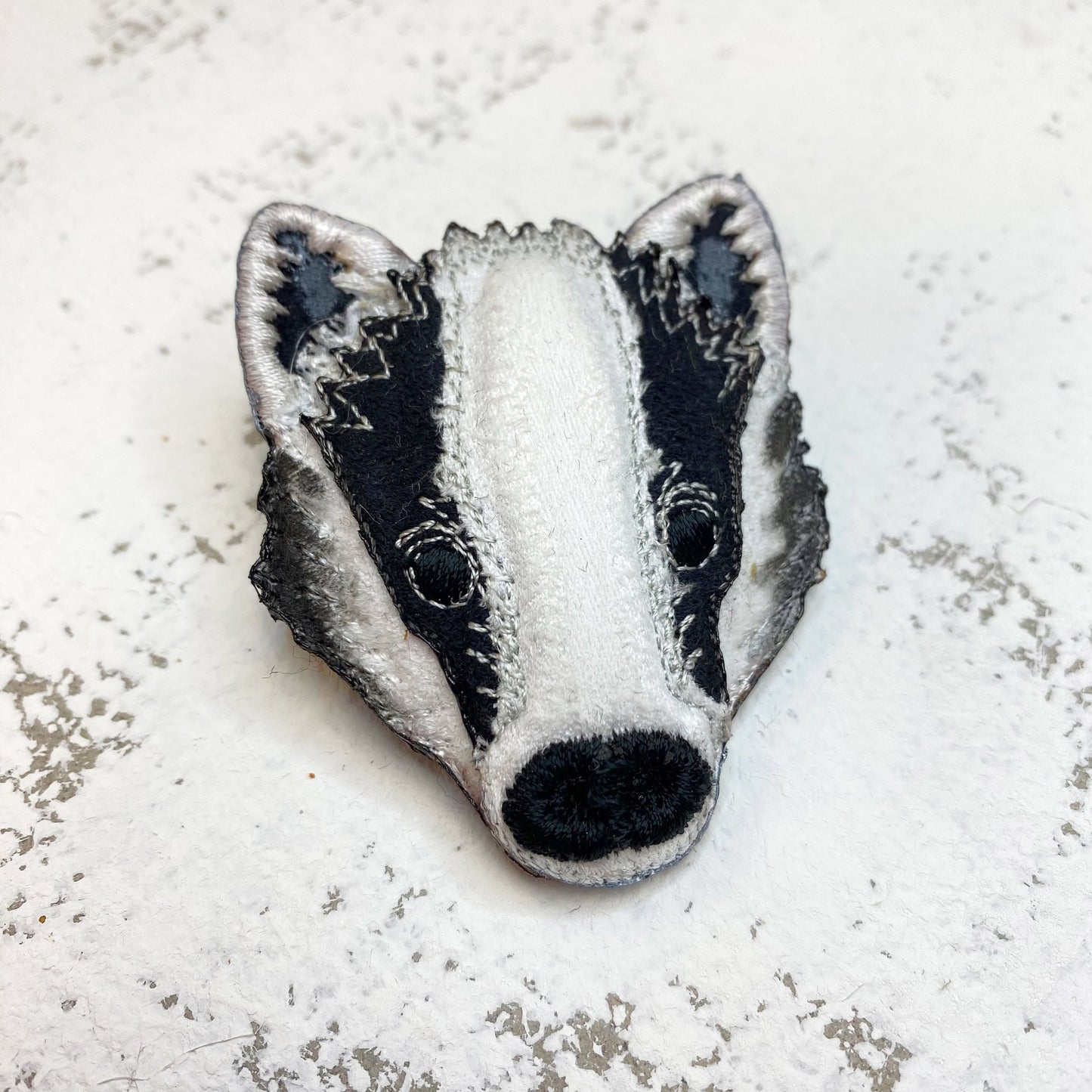 Embroidered and painted fabric badger brooch